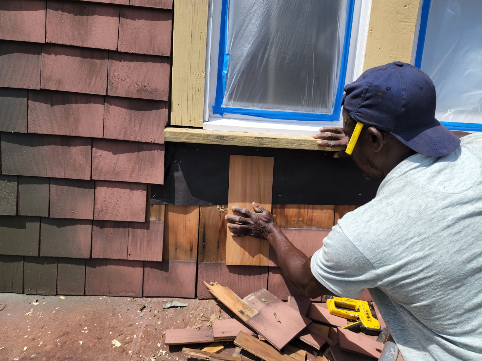 Hendricks Home Improvement carpenter replacing cedar shingle siding around a masked window